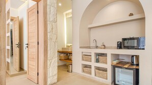 A modern kitchen with built-in appliances, a stone accent wall, and open shelving with baskets. - Bungalow Medina - Heated swimming pool not overlooked (Marrakech)