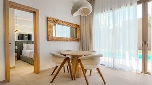 A modern hotel room with a large bed, a round table with chairs, a large mirror, and a view of a pool. - Bungalow Medina - Heated swimming pool not overlooked (Marrakech)