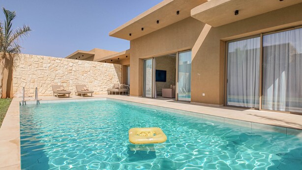 A swimming pool with clear water, a yellow float, and a stone wall. - Bungalow Medina - Heated swimming pool not overlooked (Marrakech)