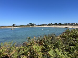 A coastal scene with a clear sky, calm water, and a sandy beach. - Beach 300m away, house for 7, garden and veranda (Plouguerneau)