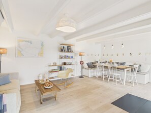 A spacious living area with a wooden dining table, white sofas, and a bookshelf. - Beach 300m away, house for 7, garden and veranda (Plouguerneau)