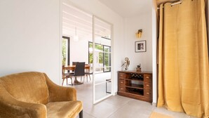 A living room with a sofa, a wooden cabinet, and a large window. - Architect-designed house in the heart of nature (Guichen)