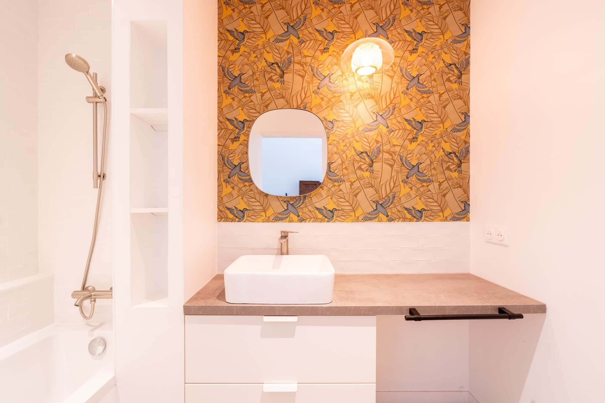 A bathroom with a white bathtub, a white sink with a rectangular basin, a mirror above the sink, and a showerhead.