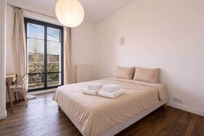 Une chambre à coucher avec un grand lit, une chaise, un radiateur et une fenêtre avec des rideaux.