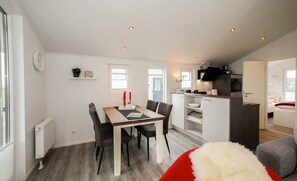 Un espace de vie compact comprenant un coin repas, une kitchenette et une chambre.