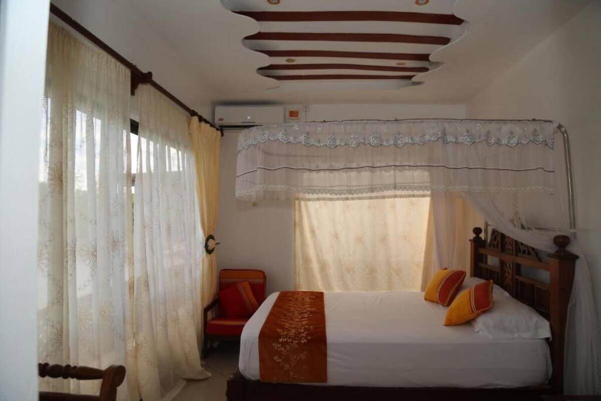 A room with a bed, a chair, and a window with curtains.