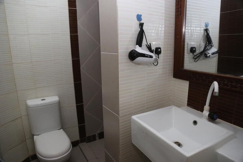 A bathroom with a white toilet, a white sink, and a mirror with a faucet.