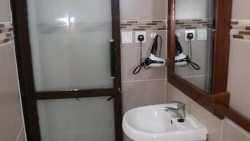 Un bagno con un lavandino bianco, uno specchio con cornice in legno e una porta in vetro satinato.