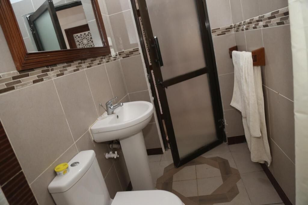 A bathroom with a toilet, sink, and a towel rack.