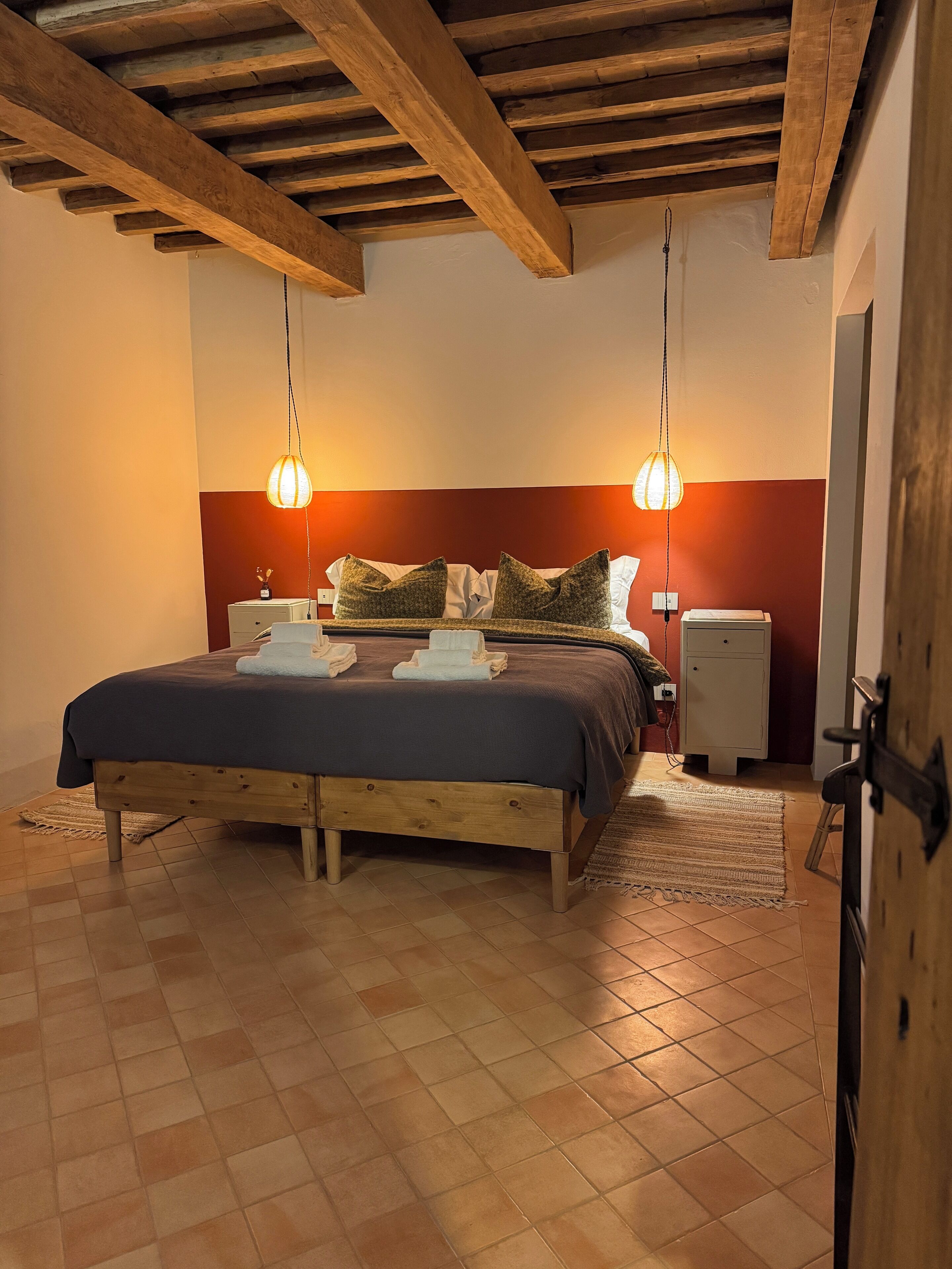 Een slaapkamer met een houten bedframe, twee nachtkastjes, een nachtkast en een kledingkast.