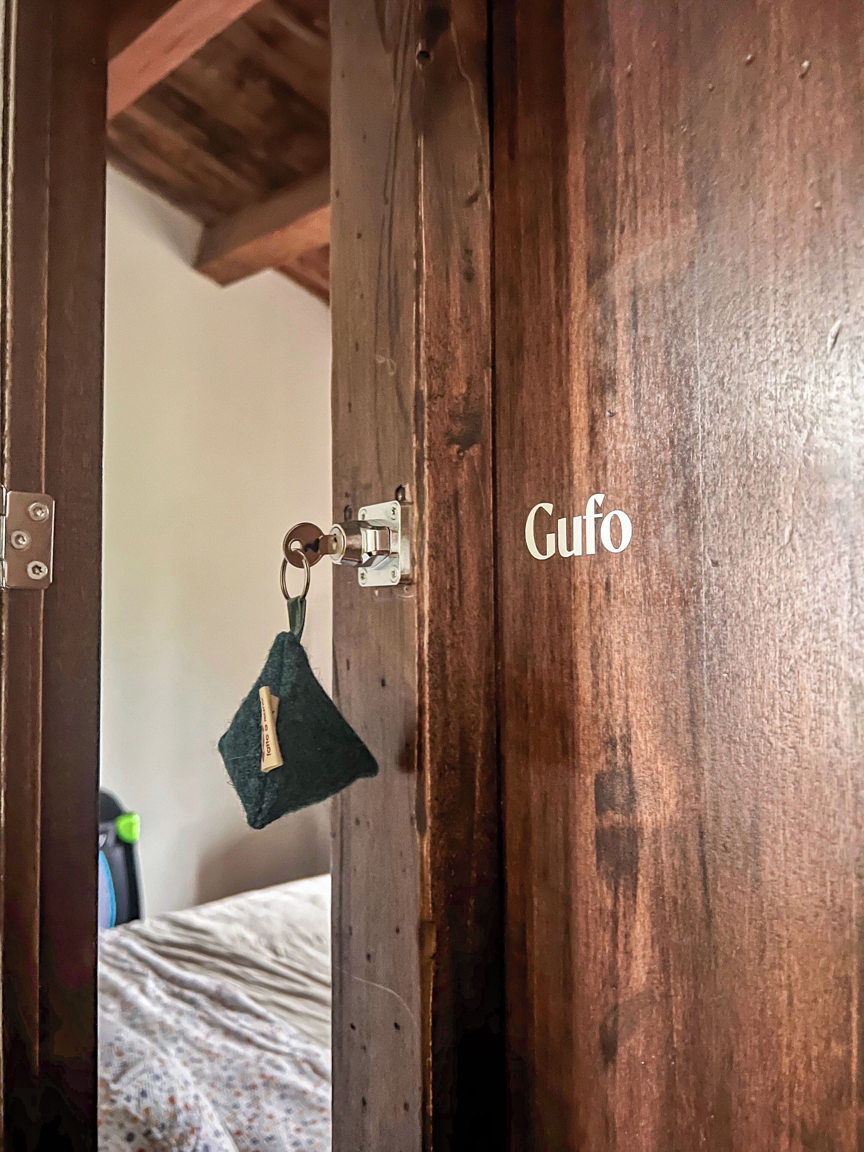 A wooden door with a keyhole and a keychain with a tag reading "Gufó".