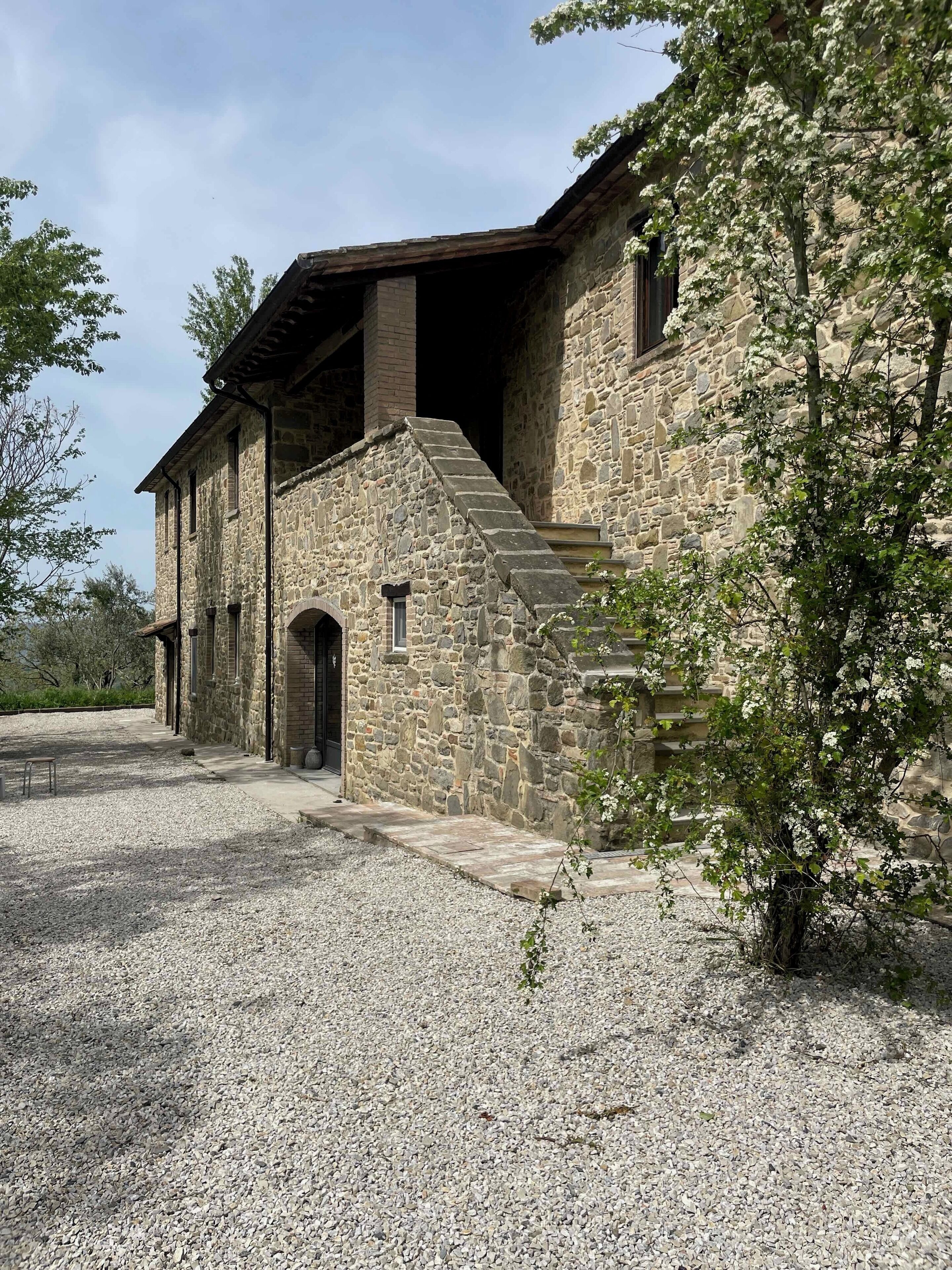 A stone building with a gravel driveway and a staircase leading to the entrance.