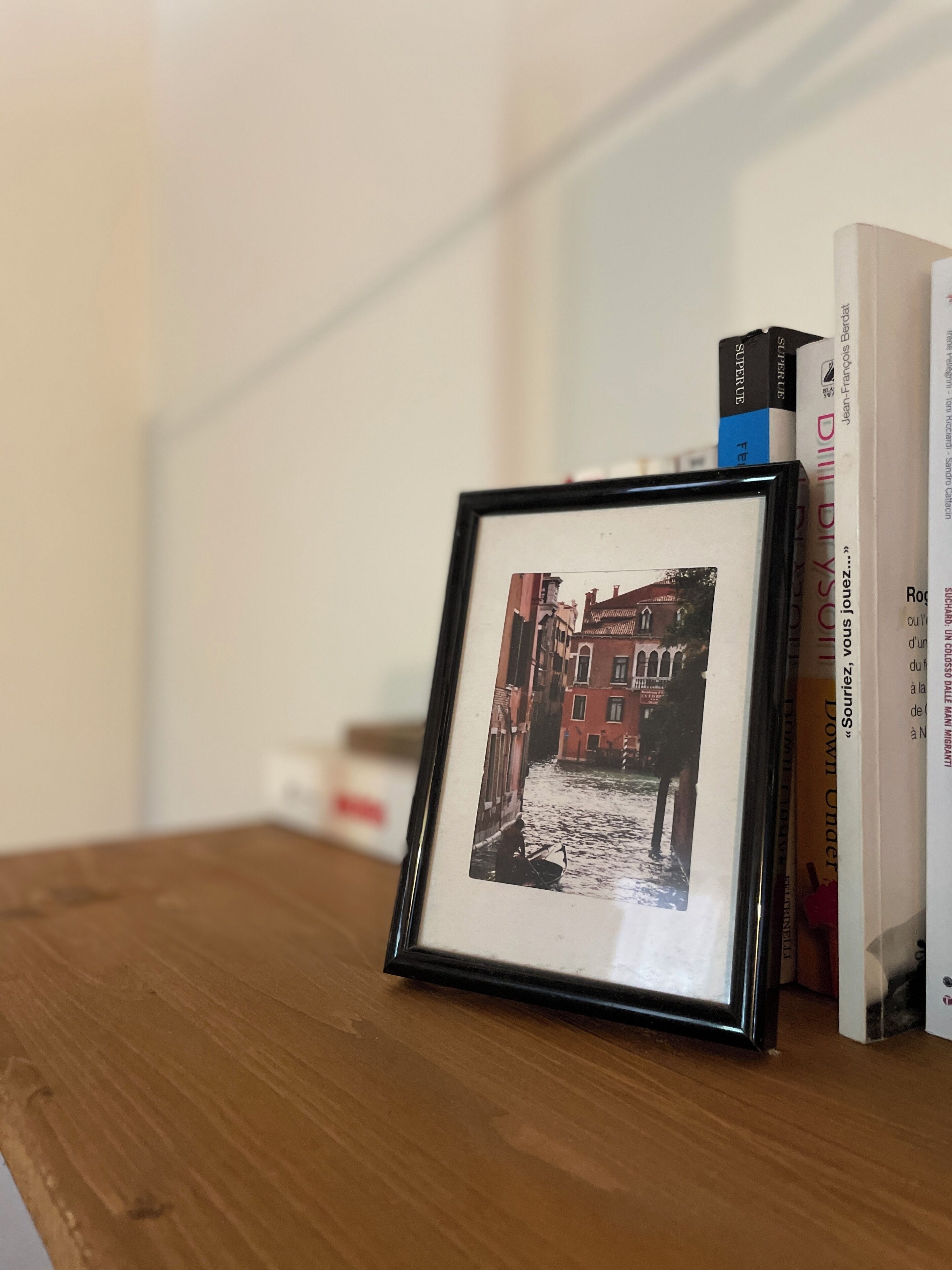 Une photographie encadrée représentant une scène de rue, posée sur une surface en bois et entourée de livres.