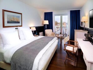 Hotelkamer met een groot bed, een bureau, een stoel, een televisie en een balkon met uitzicht.