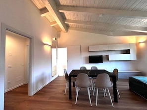 A modern interior with a dining area, built-in TV, and wooden ceiling beams. - Casa Paolina Apartment - Lomazzo (Lomazzo)