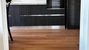 Une cuisine moderne avec des meubles de couleur sombre, un réfrigérateur en acier inoxydable et un pare-feu en carreaux.