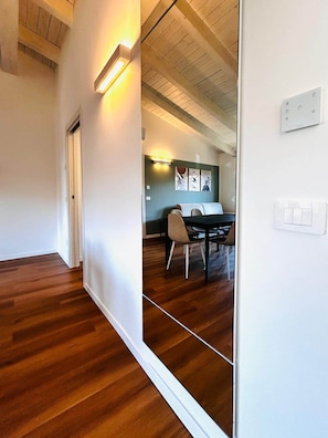 A hallway with wooden flooring, a dining area with a table and chairs, and a ceiling with exposed beams. - Casa Paolina Apartment - Lomazzo (Lomazzo)