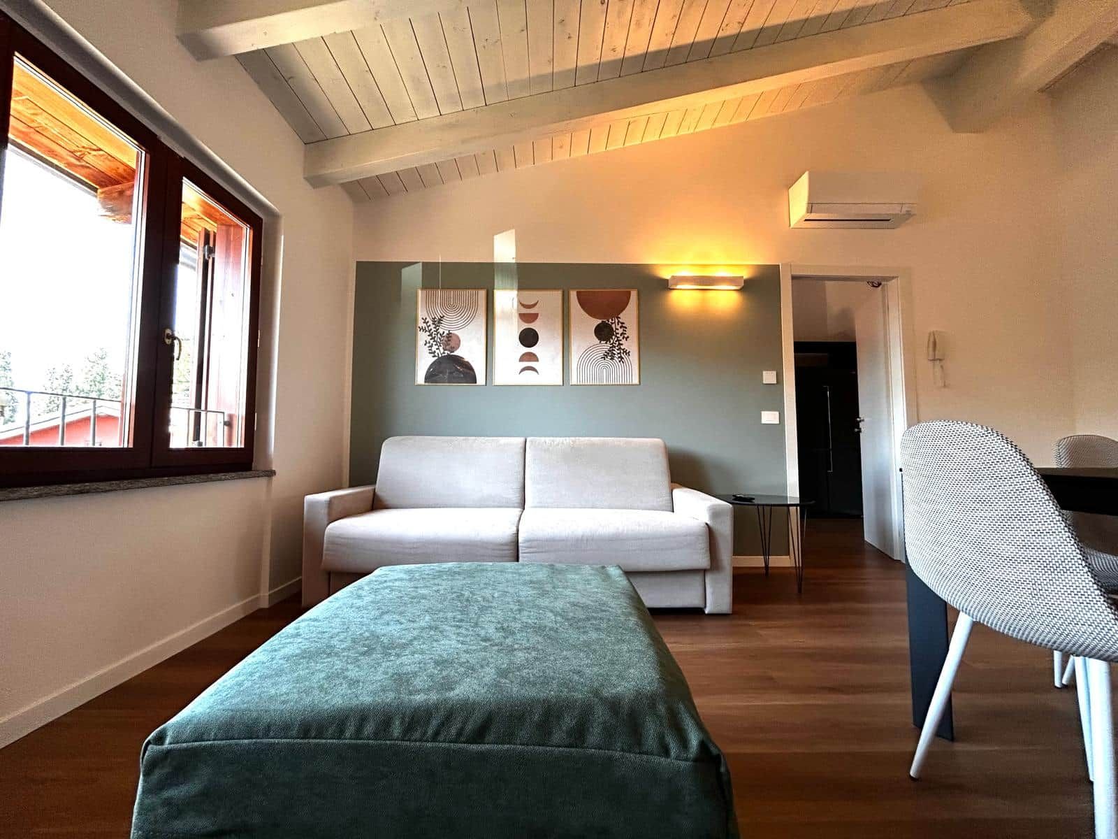 Une pièce comprenant un canapé, une petite table, une chaise et des œuvres d’art accrochées au mur.