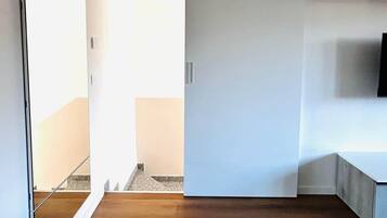 Ein modernes Interieur mit Holzboden, einer weißen Tür und einer sichtbaren Treppe.