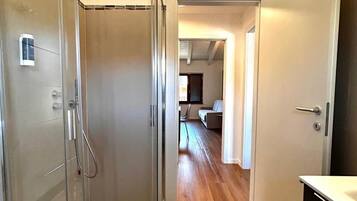 Une salle de bain moderne avec une douche à parois de verre, un plancher en bois et un porte-serviettes apparent.
