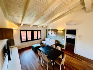A compact living space with a dining area, a sofa, a TV, and a kitchenette. - Casa Paolina Apartment - Lomazzo (Lomazzo)