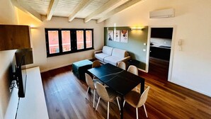 A compact living space with a dining area, a sofa, a TV, and a kitchenette. - Casa Paolina Apartment - Lomazzo (Lomazzo)
