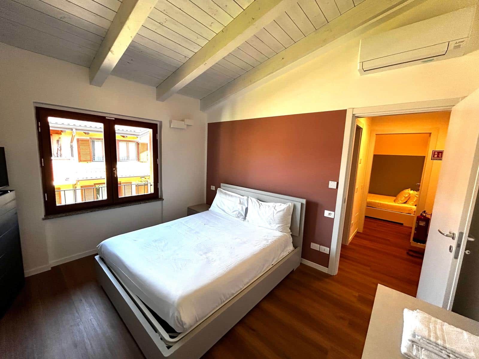Une chambre à coucher avec un lit, une fenêtre, une porte et une petite table de chevet.