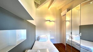 A modern hotel room with a long bed, a small bedside table, a mirror, and a wardrobe. - Casa Paolina Apartment - Lomazzo (Lomazzo)