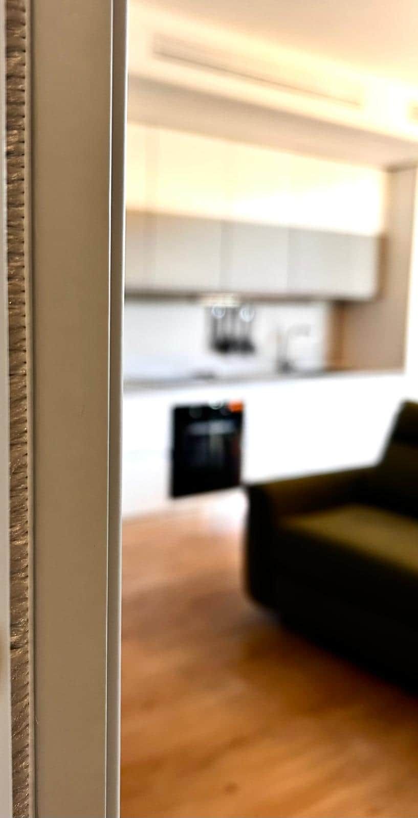 A blurred view of a modern kitchen with white cabinets and a dark countertop.