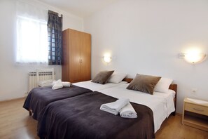 A double bed with a wooden headboard, two bedside tables, a wardrobe, and a window with curtains. - Spacious Apartment in Umag (Umag)