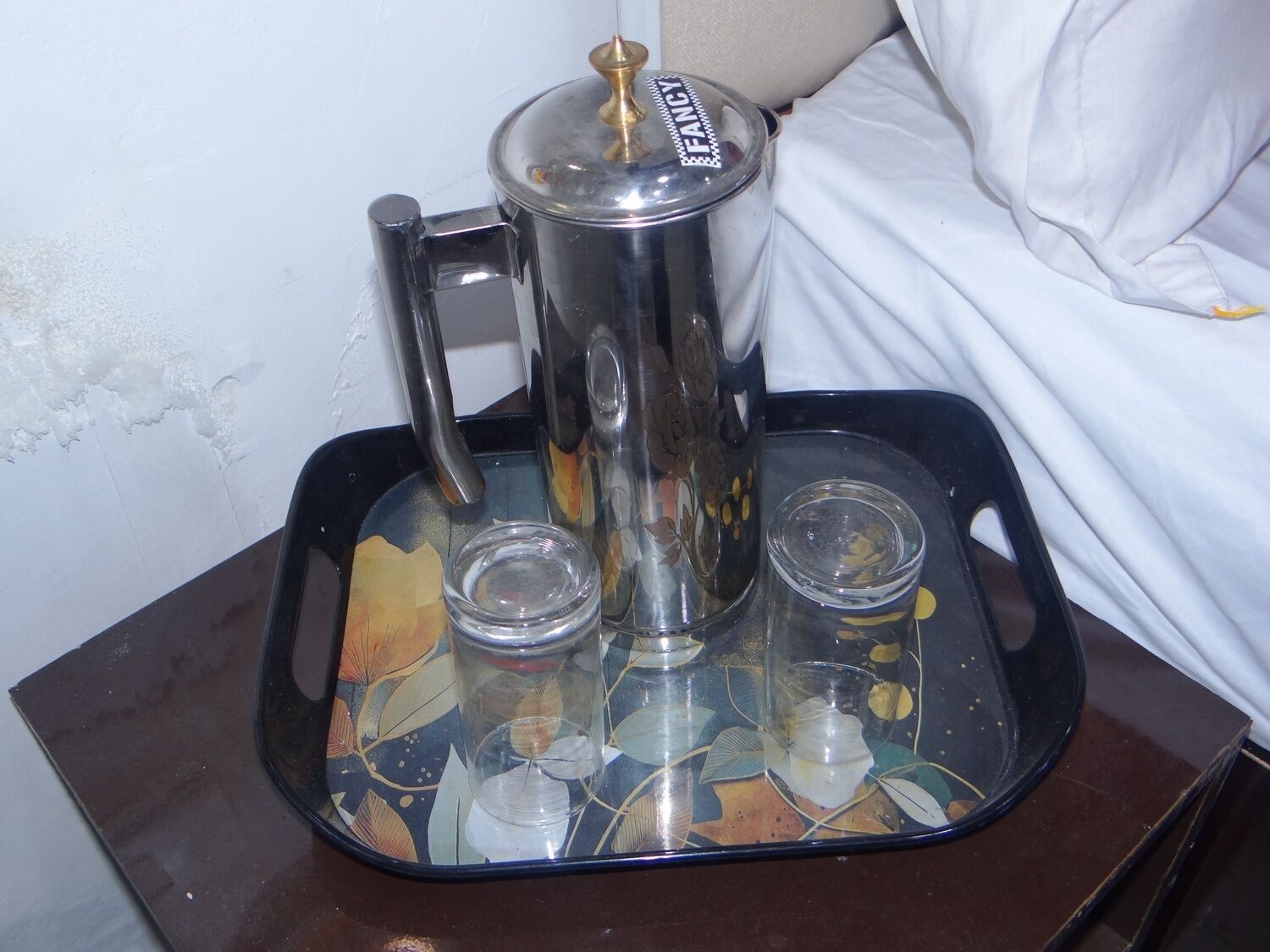 A coffee maker on a tray with two glasses.