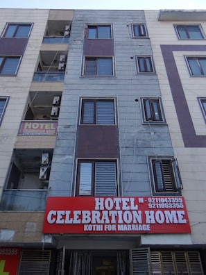 A multi-story building with a prominent red sign for a hotel and celebration home. - Hotel Celebration Home (New Delhi)