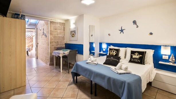 A bedroom with a bed, a desk, and a chair. There is a window and a door leading to another room. - Elegant Ground-floor Apartment in Porto Cesareo Design Moderno Vicino al Mare (Porto Cesareo)