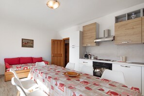 A compact kitchen with white cabinets, a stove, and a dining area with a table set for two.