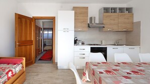 Una habitación de hotel compacta con cama, kitchenette pequeña, zona de comedor y baño.