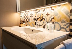 A modern bathroom with a large sink, a mirror above it, and a decorative tile backsplash. - LE VIGNE MOROSINA (Cessalto)