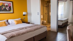 Een hotelkamer met een groot bed, een douchegedeelte en een klein zithoekje.