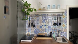 Una cocina con un refrigerador de acero inoxidable, una encimera de madera, un fregadero y un protector contra salpicaduras con baldosas azules y blancas.