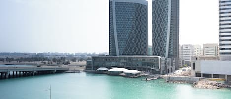 A waterfront view with modern buildings, a bridge, and a marina.