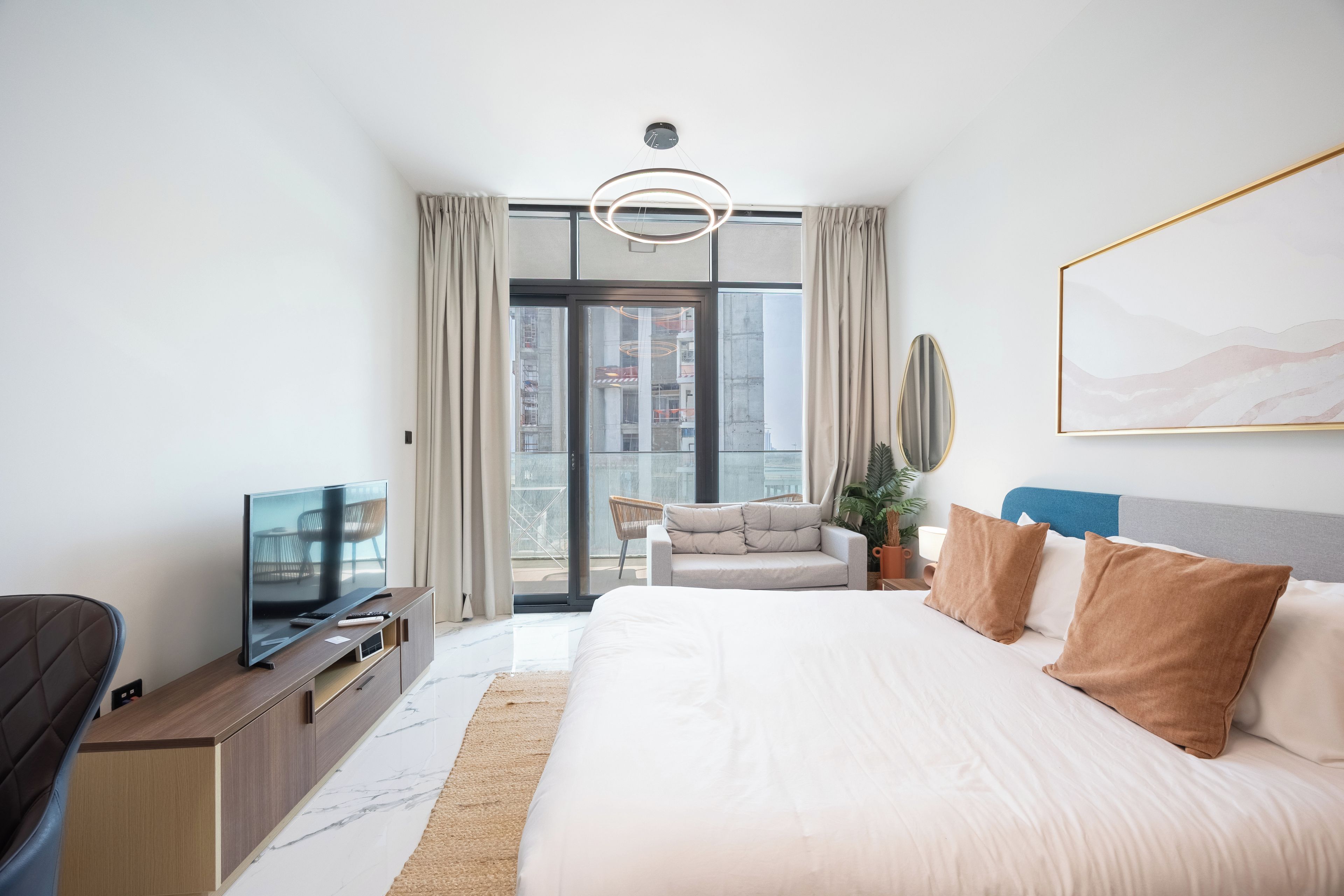 Moderni hotellihuone, jossa on suuri sänky, taulutelevisio, sohva ja ruokailutila.