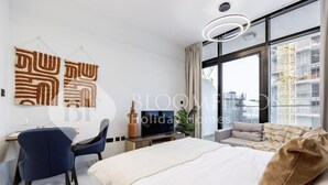A modern hotel room with a bed, a desk, a chair, a television, and large windows offering a city view. - Elegance Stu Al Maryah Vista (Abu Dhabi)