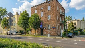 A multi-story brick building with a sign indicating a business on the ground floor. - Cozy Studio for Two | Close to Metro | Pet-Friendly (Warszawa)
