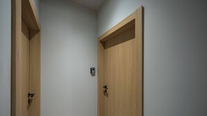 Two wooden doors with a small light switch on the wall between them. - Cozy Studio for Two | Close to Metro | Pet-Friendly (Warszawa)