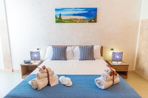 Een hotelkamer met een bed, twee nachtkastjes, een schilderij van een landschap en handdoeken op het bed.