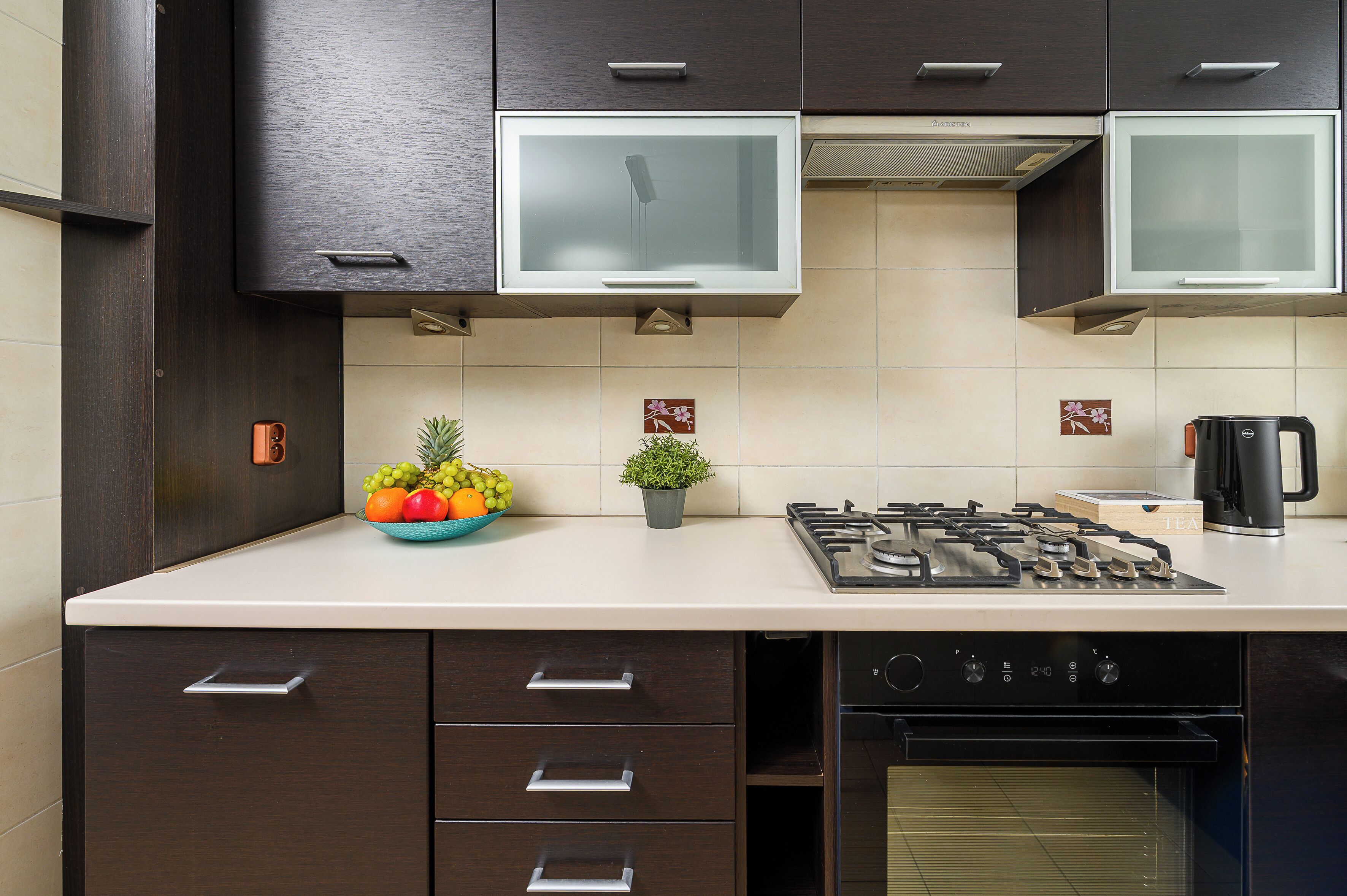 A modern kitchen with dark cabinetry, a gas stove, and a coffee maker.