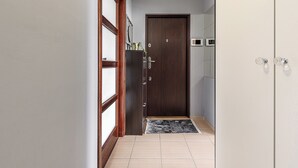 A hallway with a wooden door, a tiled floor, and a small rug. - Lumina 3-rooms apartment with parking (Warsaw)