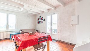 Una habitación con una mesa roja, un banco de madera y vistas a través de una puerta.