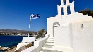 Un bâtiment blanc doté d’un clocher, d’un drapeau et offrant une vue sur la mer.