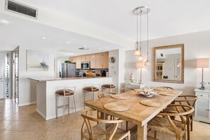 Eine moderne Küche mit einer zentralen Kochinsel, einem Holzespeisetisch mit gewobenen Tischsets und einem großen Spiegel an der Wand.