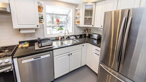 A modern kitchen with stainless steel appliances, white cabinetry, and a window providing natural light. - 4BR Family Retreat Near Annapolis w/ Large Yard (Annapolis)